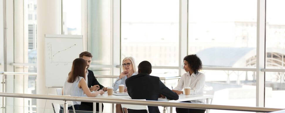 Diverse group of coworkers in an informal meeting, illustrating the importance of inter-departmental  communication.