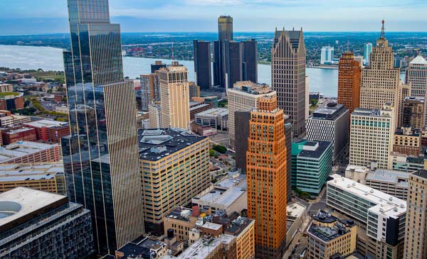 Detroit skyscrapers, the Detroit River, and the skyline under partly cloudy sky.