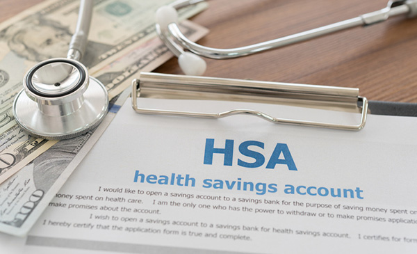 Health Savings Account form on a clipboard with a stethoscope and U.S. dollar bills, symbolizing medical expenses and financial planning.