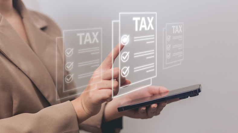 A person holding a tablet and interacting with virtual tax documents displayed as floating digital screens. Each document is labeled “TAX” and shows checkmarks next to listed items.