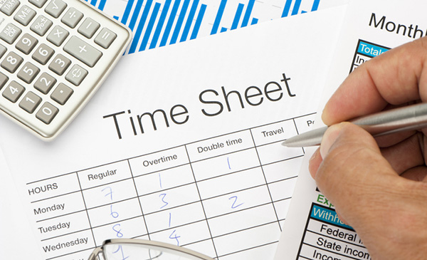 A close-up of a timesheet labeled “Time Sheet” with handwritten numbers in columns for regular hours, overtime, double time, and travel.