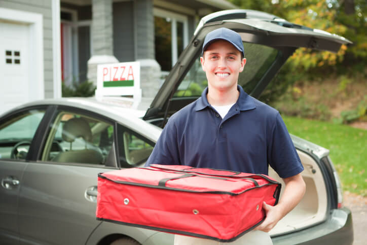 Pizza deliveryman holding pizza bag in front of car