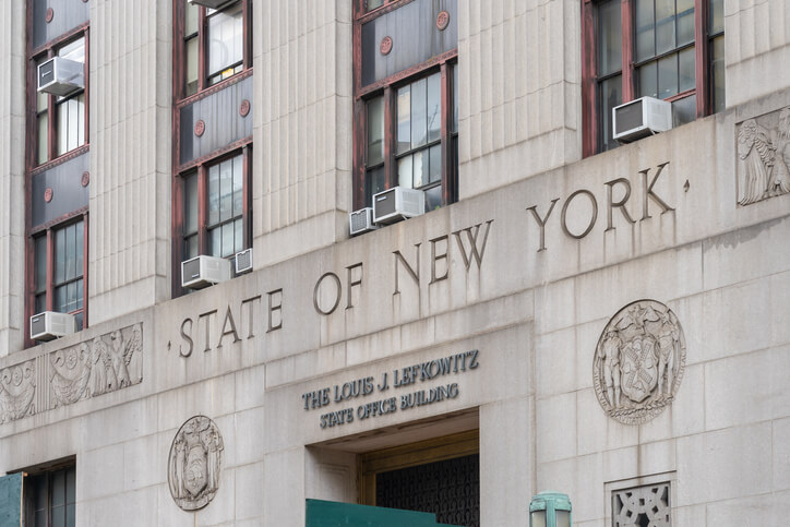 Front facade of the Louis J. Lefkowitz State Office Building in New York, with 'STATE OF NEW YORK' and the building name inscribed. The structure has multiple windows, some with air conditioning units, and decorative carvings flanking the text.