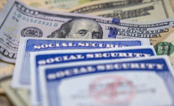 social security cards on pile of U.S. currency