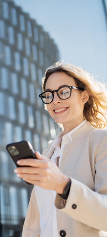 Woman smiles while looking at her phone, symbolizing satisfaction with taking key actions.