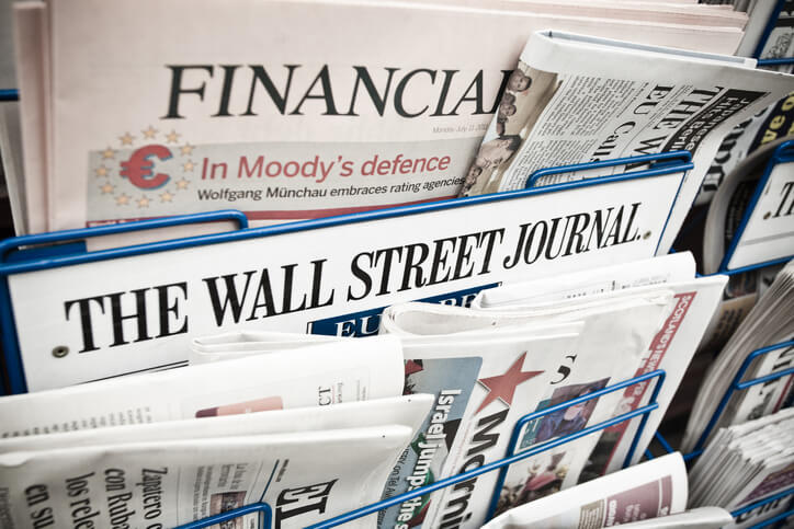 A newsstand display featuring newspapers, with "FINANCIAL TIMES" and "THE WALL STREET JOURNAL" prominently visible.