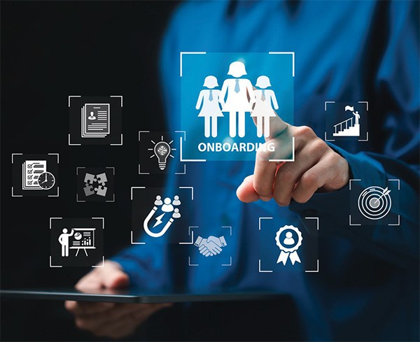 Accompanying image for article titled "Why Implementing Self Service is Worth It." Person in a blue shirt interacting with a digital onboarding interface, featuring icons for documents, ideas, handshake, and goals, while holding a tablet.